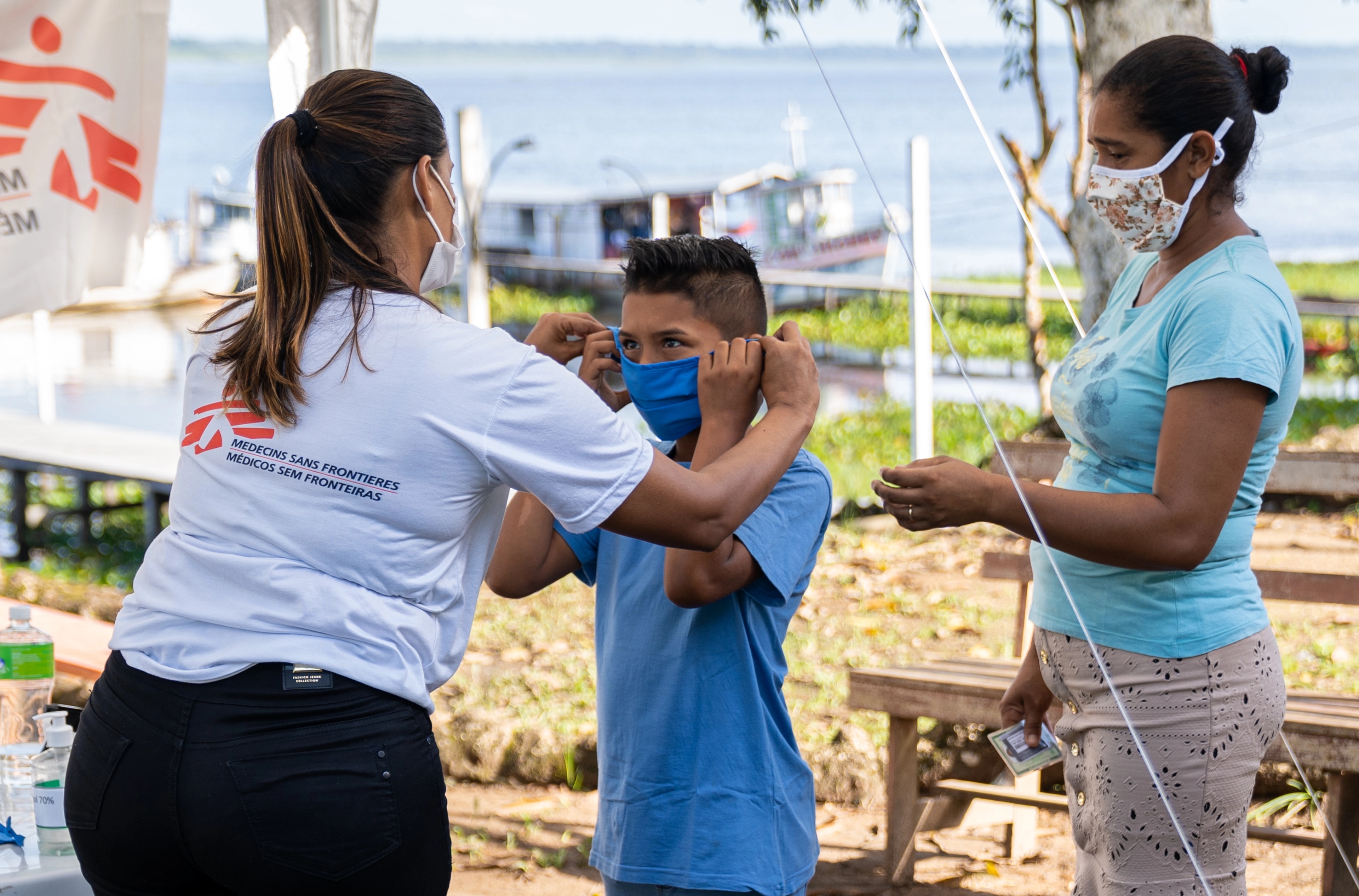 A woman in an MSF shirt helps a boy with a face mask