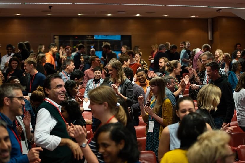 A large group of people at a conference pass by each other and chat