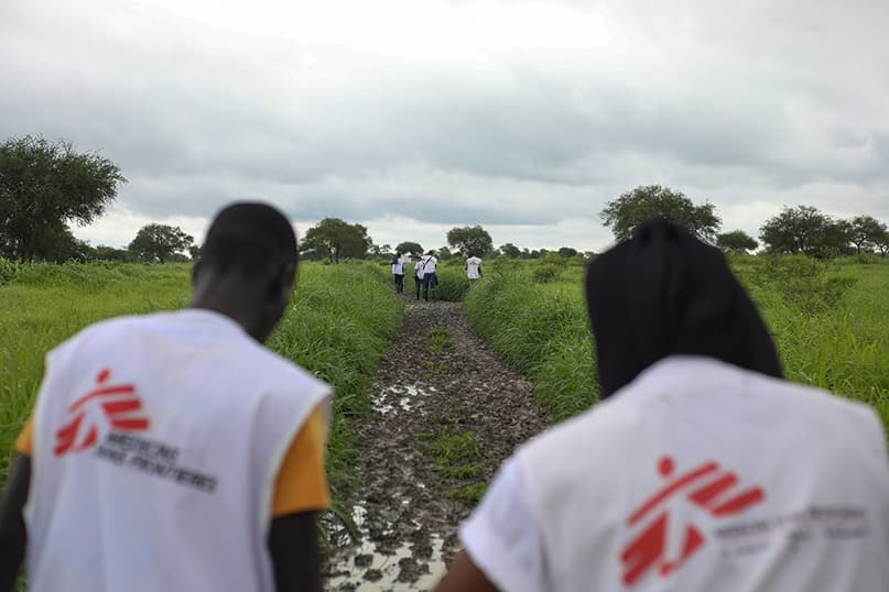 Two people in MSF vests face away from the camera
